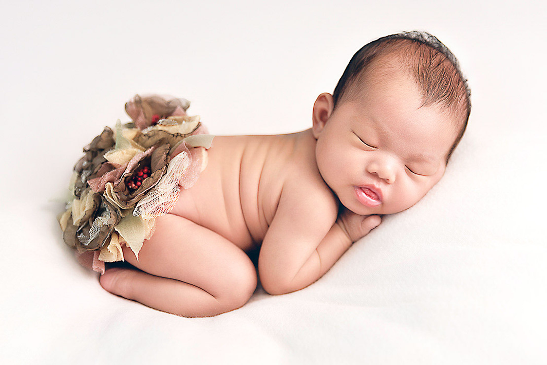 how much does newborn photoshoot costs, baby sleeping on a white blanket