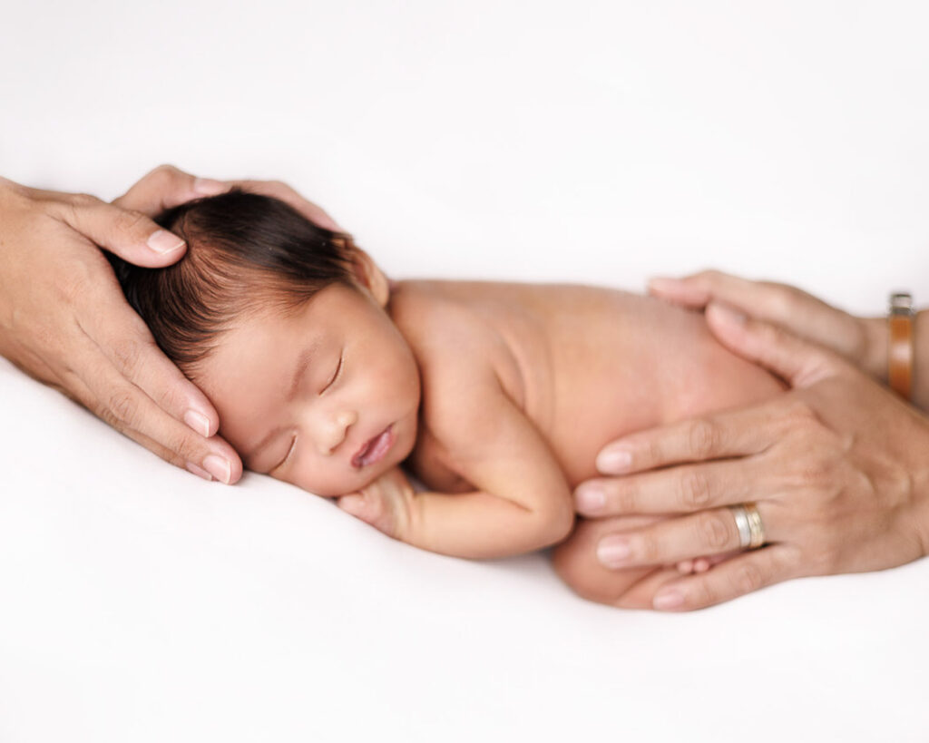 parents hands holding their newborn baby