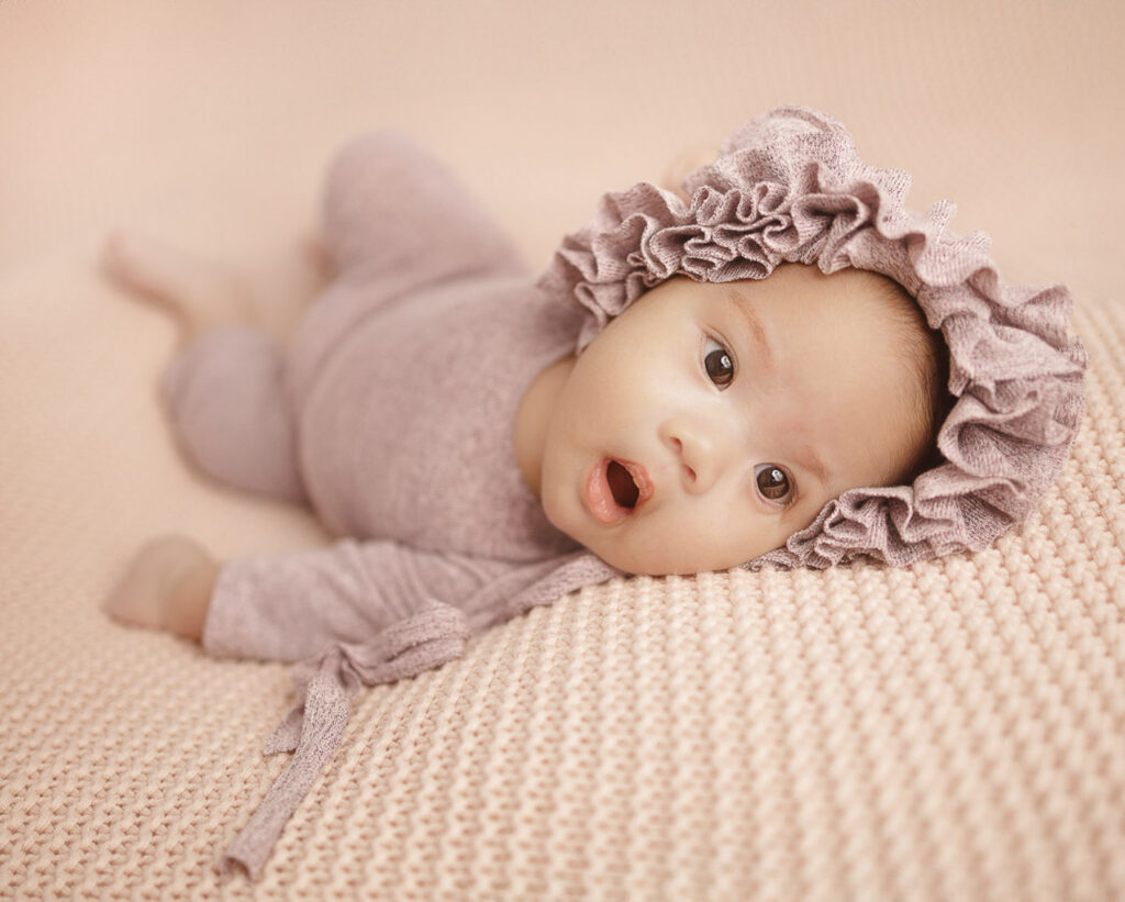 Baby lying on a bed wearing lilac outfit