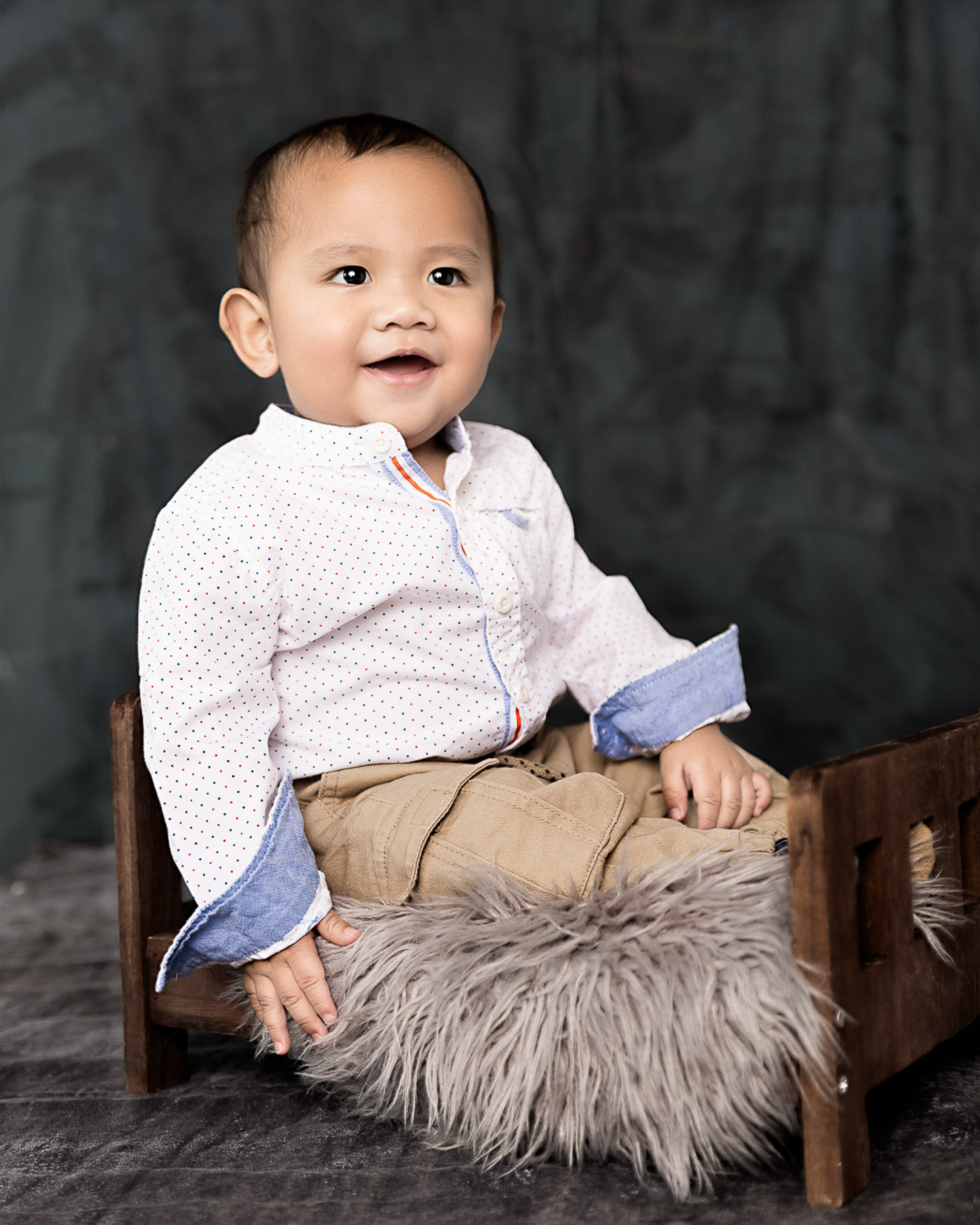 Toddler smiling, Manila Kids, sitting on mini bed